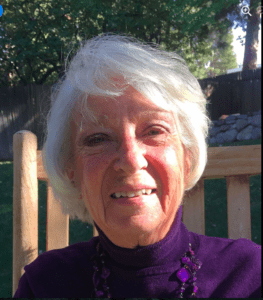 A smiling white-haired woman in a chair.